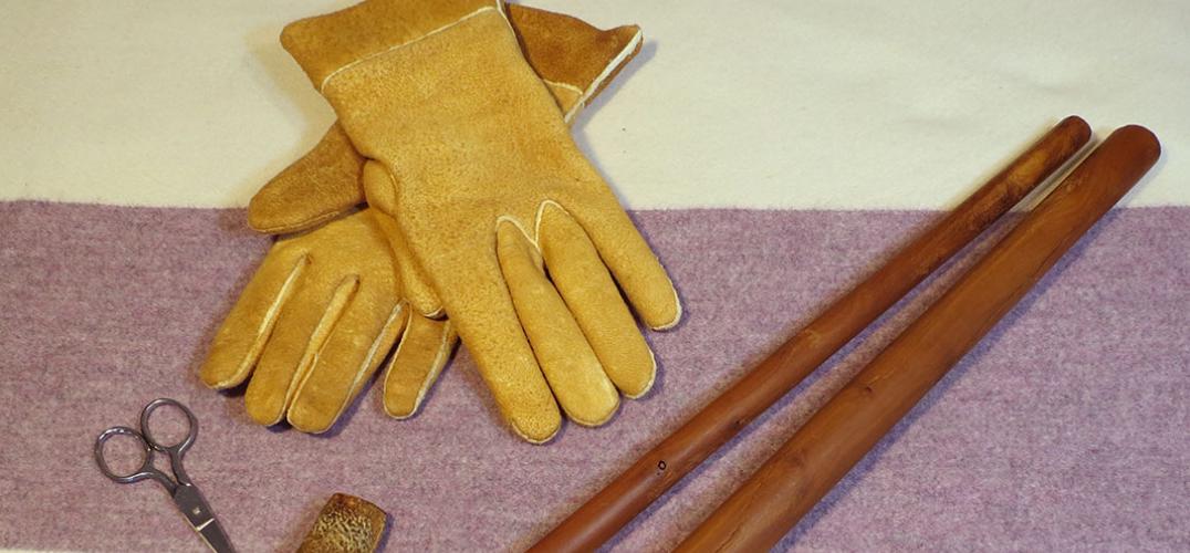 Handmade gloves and tools used to make them, laid out on a blanket