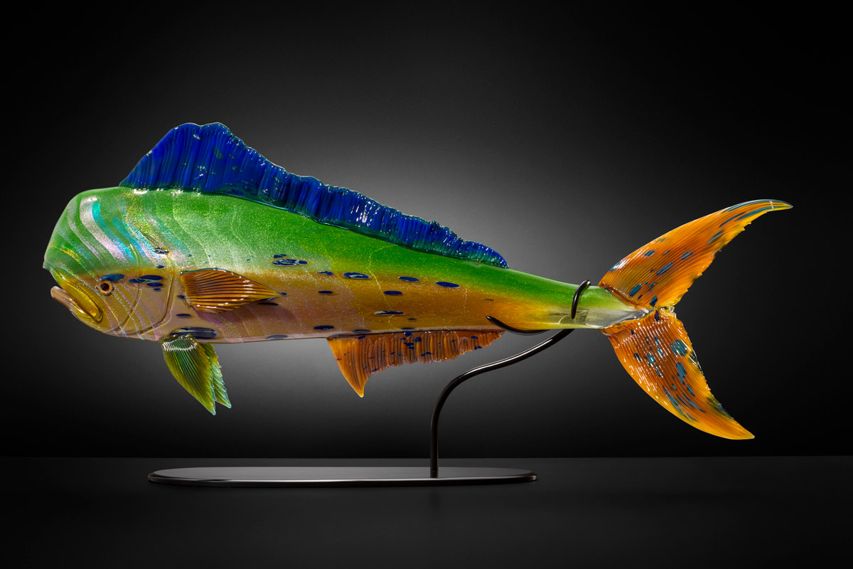 Glass sculpture of a colorful mahi mahi fish affixed to a metal pedestal