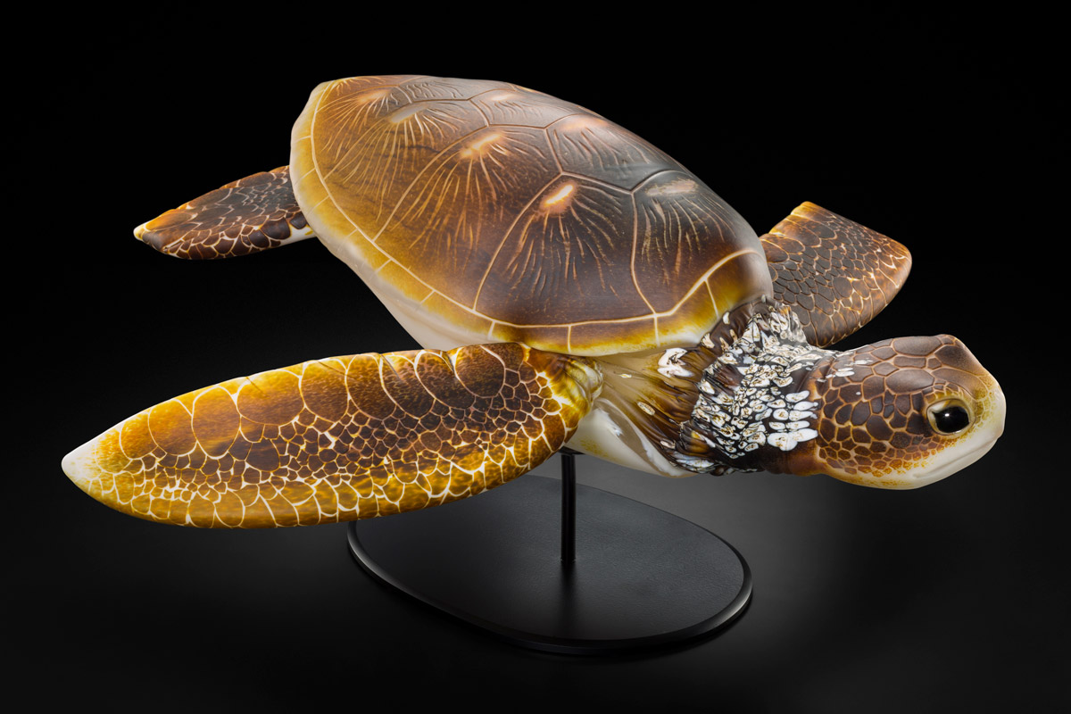 A photorealistic glass sculpture of a turtle perched upon a pedestal. 