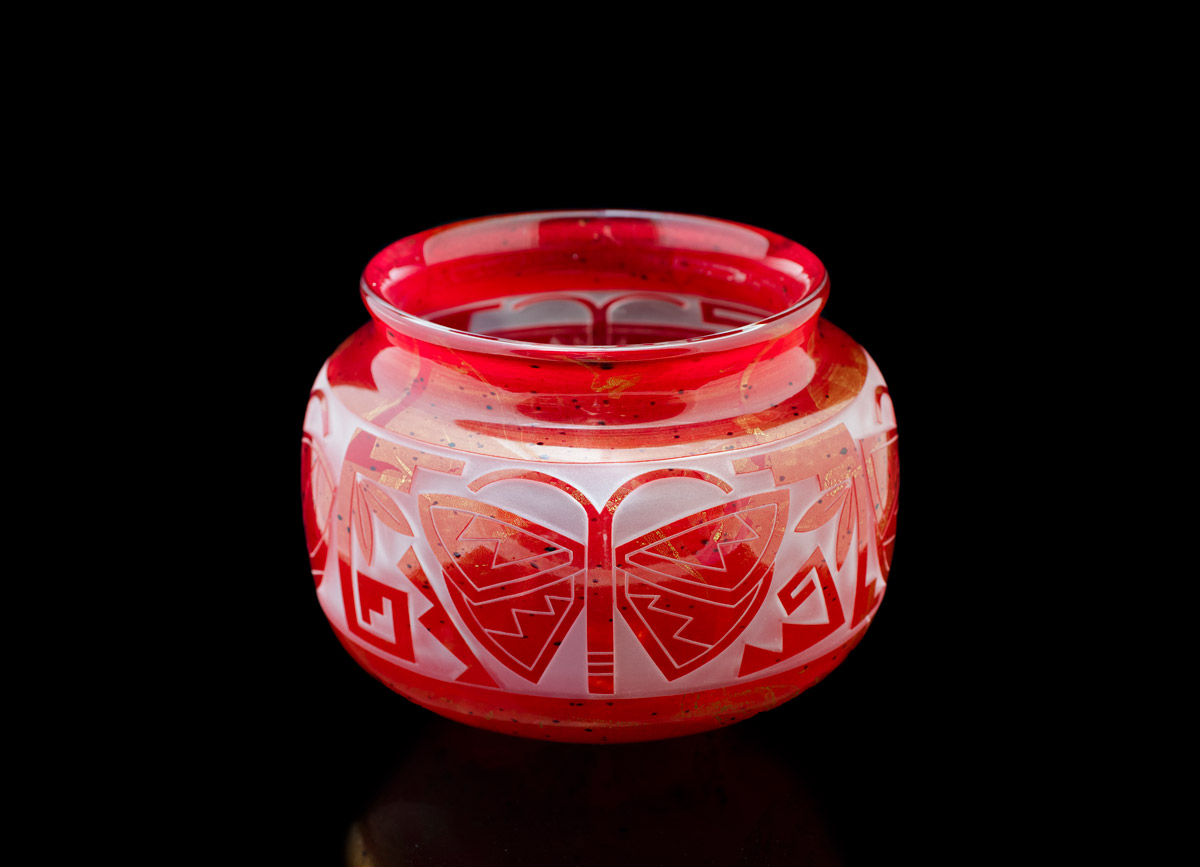 A red glass pot with insect life details