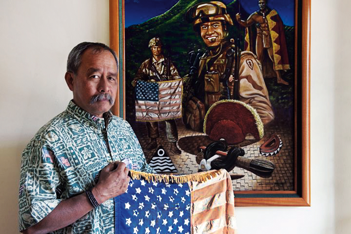 Vietnam veteran Allen Hoe (Native Hawaiian) holds a flag that he and his son, First Lieutenant Nainoa Hoe (in painting) carried into battle