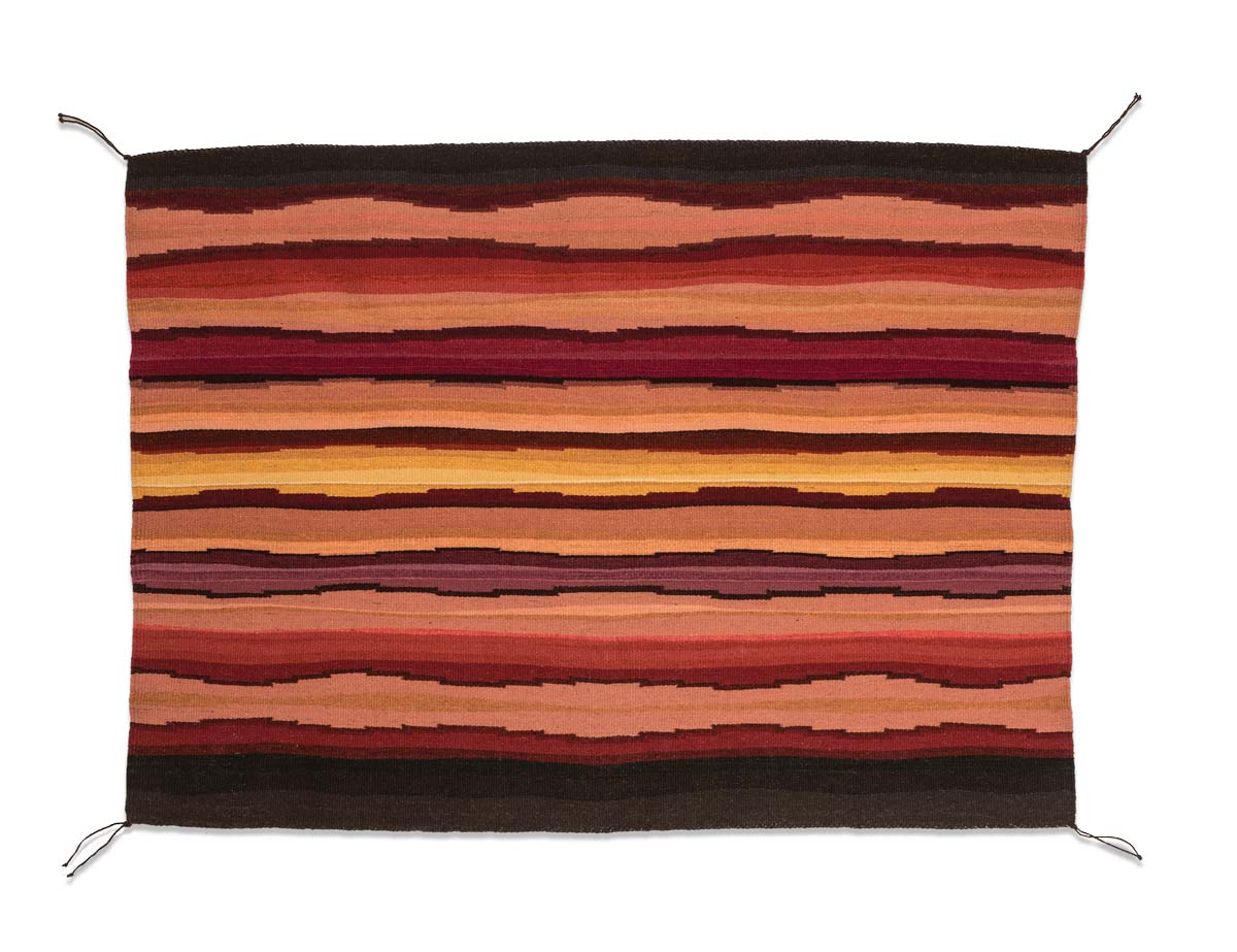 Woven wool tapestry decorated with vibrant high contrast black , brown, and red, and yellow geometric patterns.