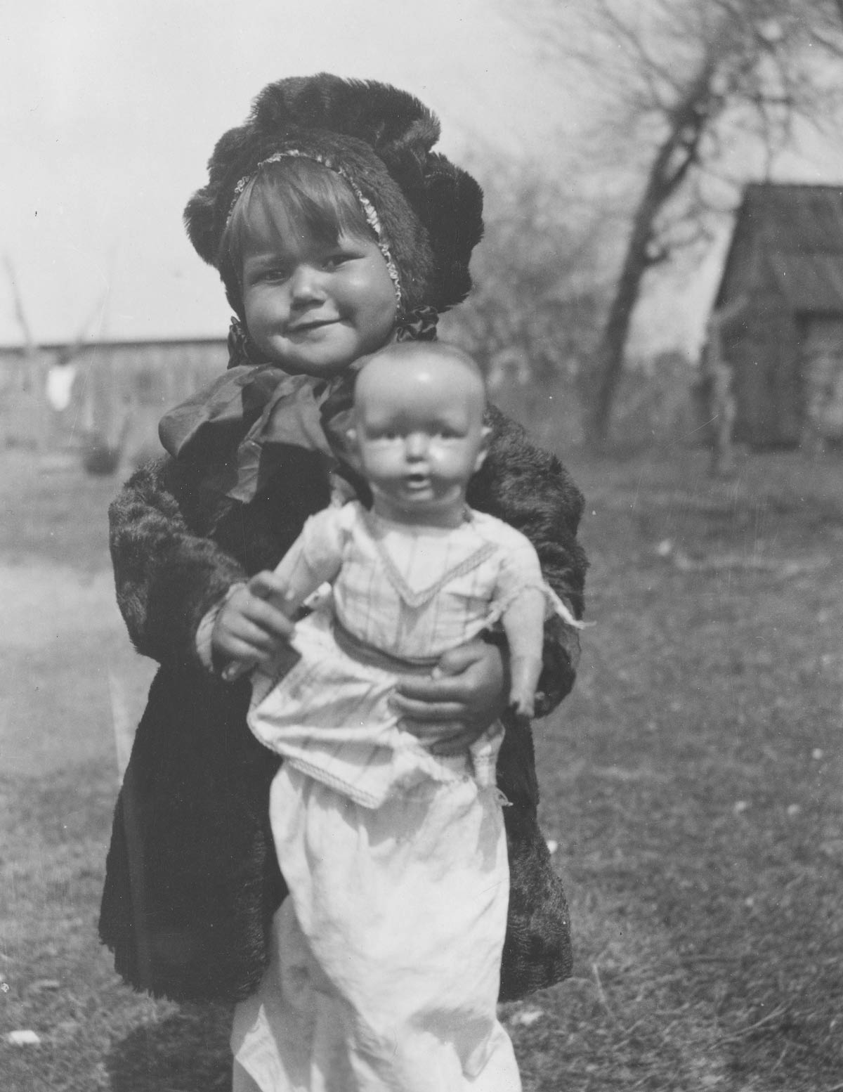 A smiling young girl holds a doll.