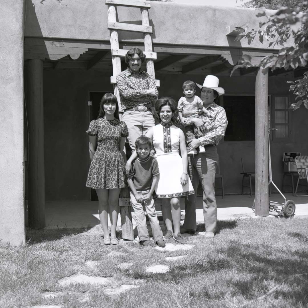 A family of 6 poses for a photograph in front of a tall wooden ladder