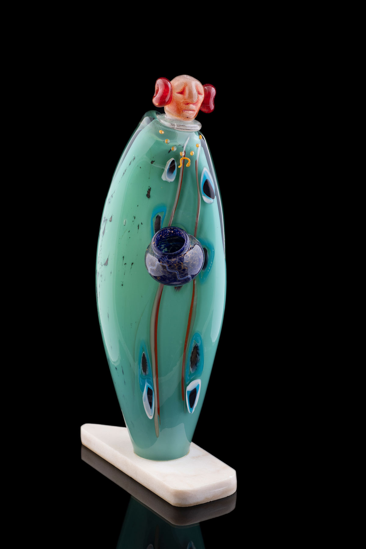 A sculpture of a person dressed in green holds a pot of water.