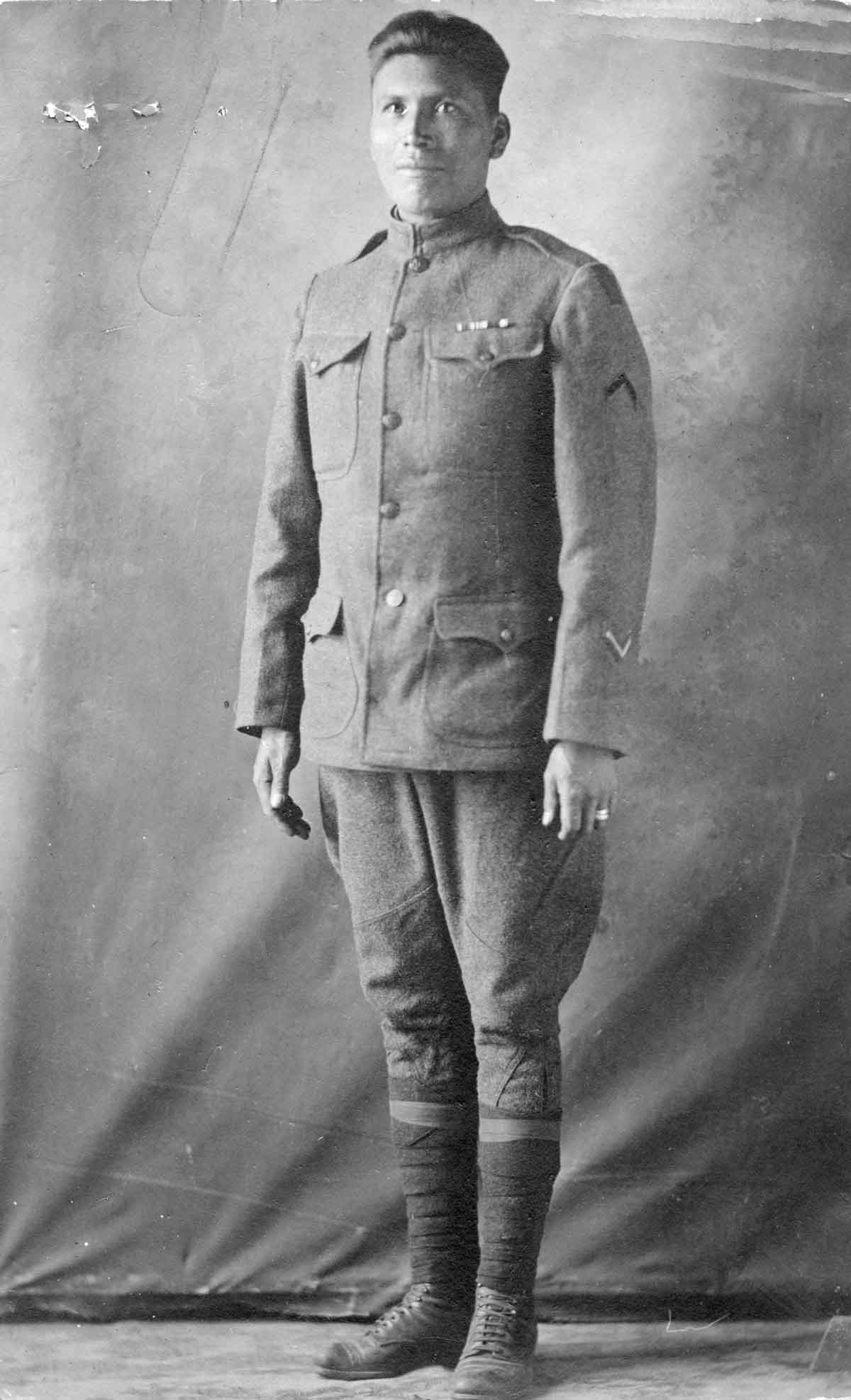 Private Robert Frank “Chief Rekwoi” Spott wears a military uniform and stands for a black and white studio portrait