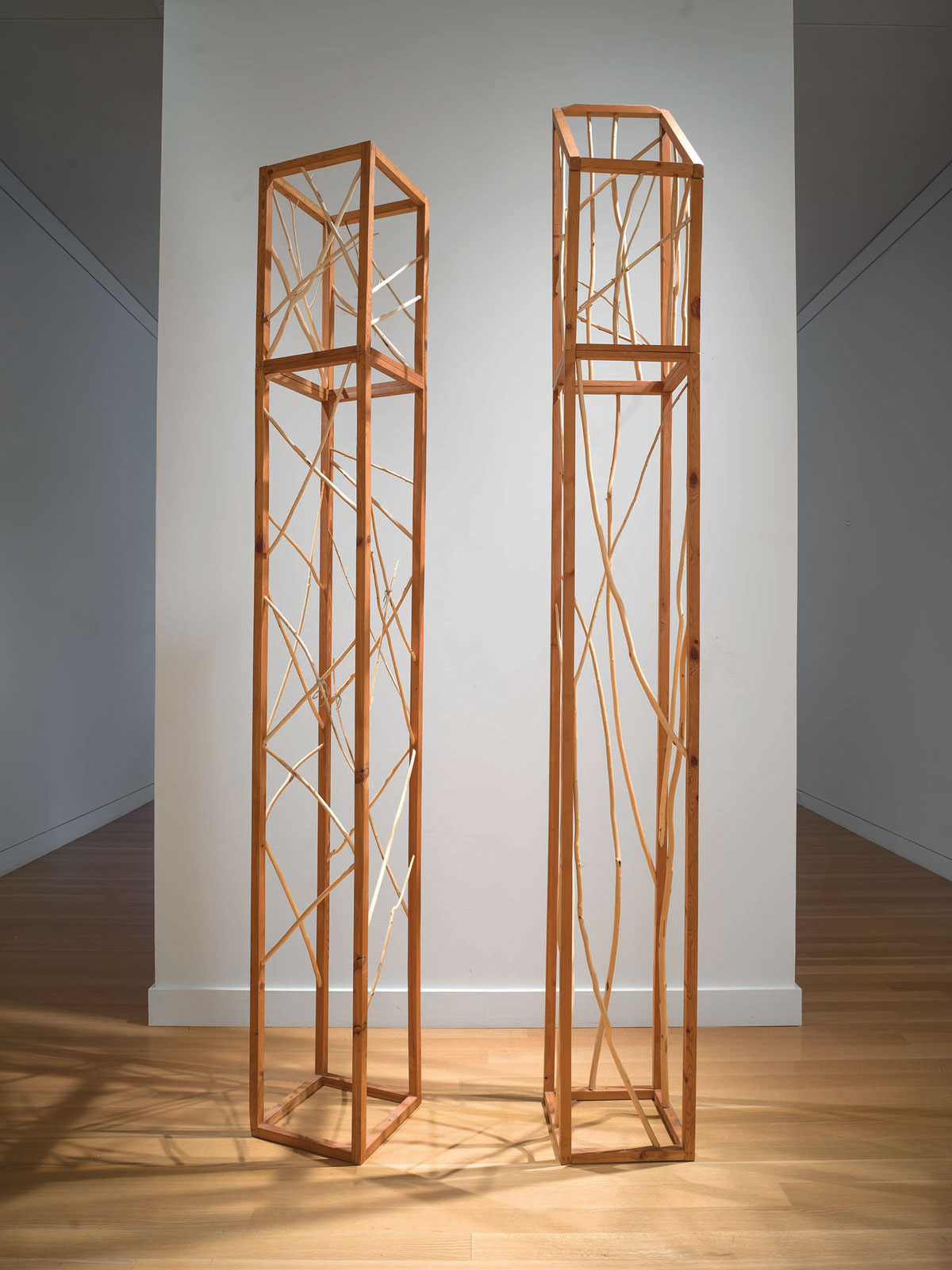 Two wooden cubic sculptures stand tall next to each other in a gallery.