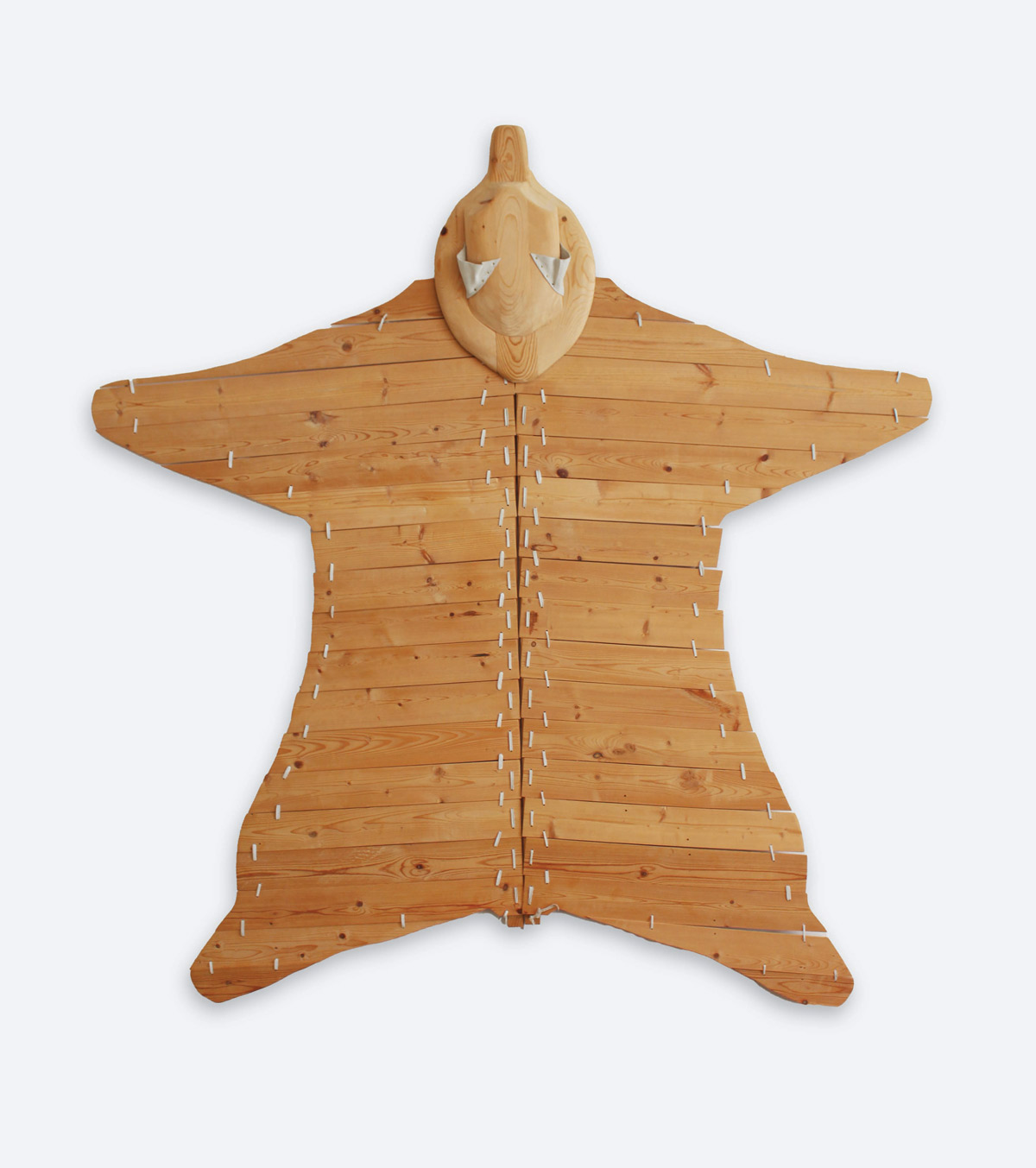 Planks of wood adhered together form the outline of a bear skin rug.