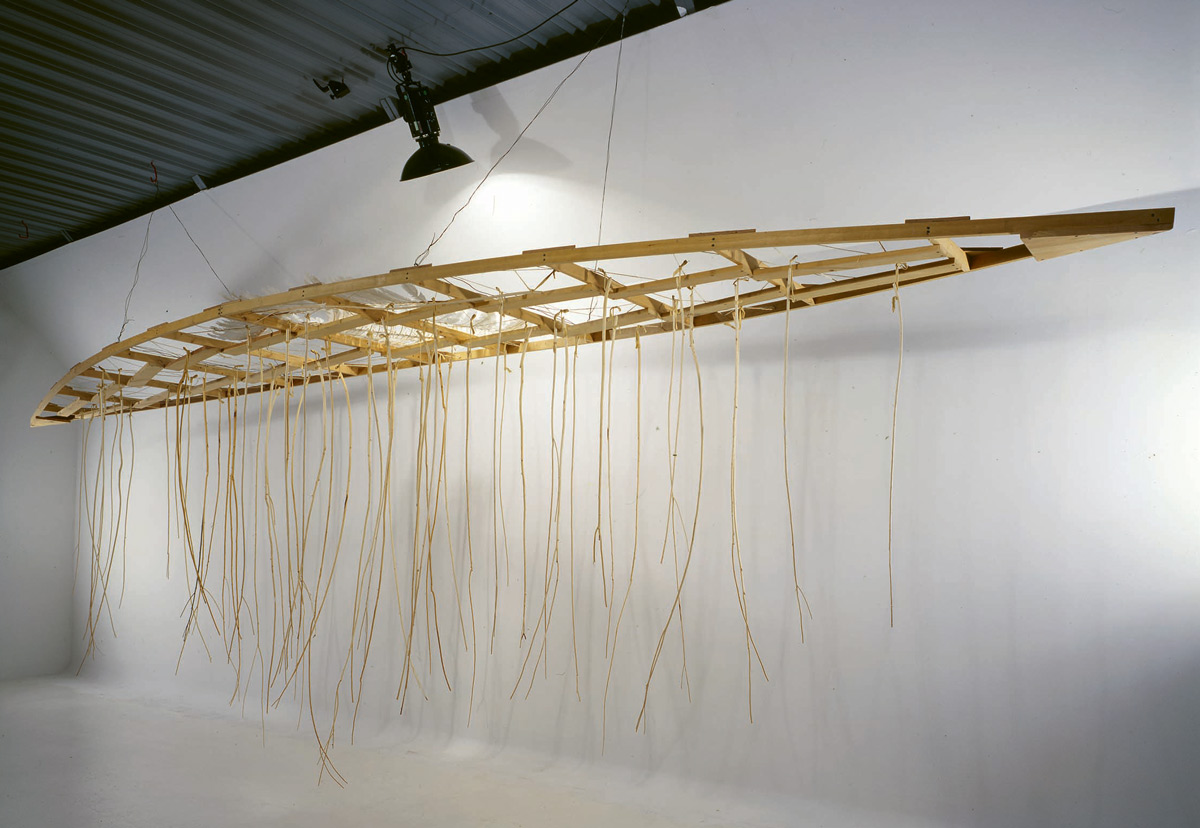 The wooden base of a canoe hangs from the ceiling of a gallery