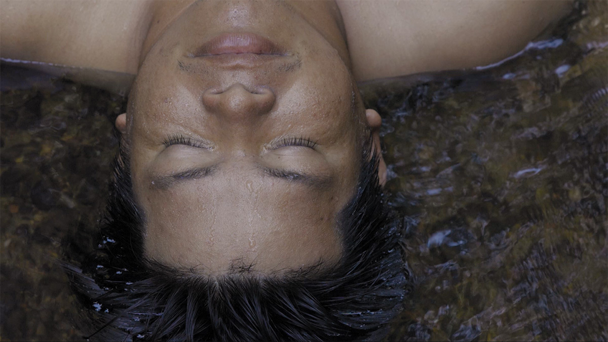 Overhead view of a man's head and neck partly submerged in shallow water