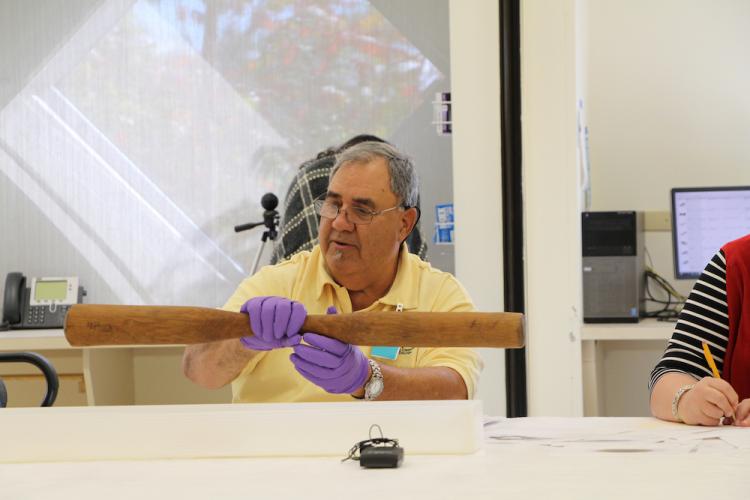 Man looking at a pestle made of cypress held in the Smithsonian collections