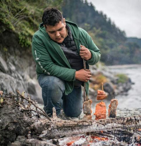 Sammy Gensaw (Yurok) prepares salmon for smoking on wooden stakes