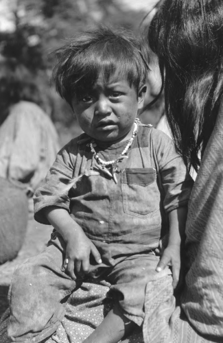 White Mountain Apache boy sitting on his mother’s lap, 1919.