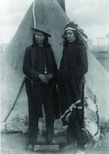 Chief American Horse, wearing a brimmed hat and revolver, shakes hands with Chief Red Cloud, Mahpina luta (1822-1909) in 1891