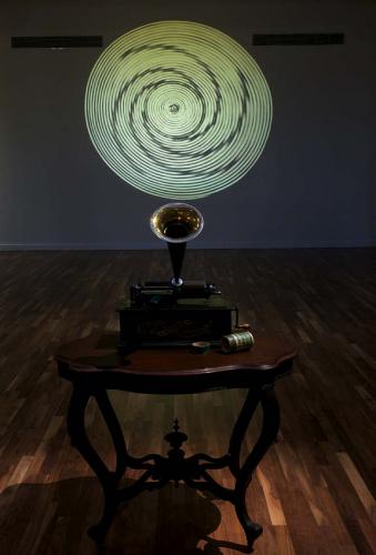 Detail of Edison cylinder phonograph (c. 1900) with an image of a Cahuilla basket projection slowly rotating behind