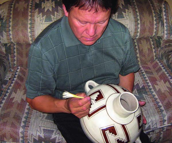 Joshua Madalena painting a pot using yucca.