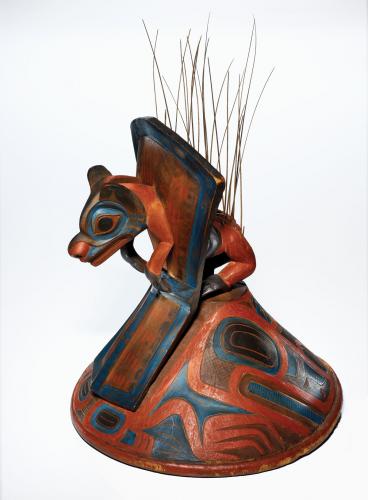 A carved wood hat topped with the Teikweidi clan's crest animal, a brown bear, jumping through a copper shield