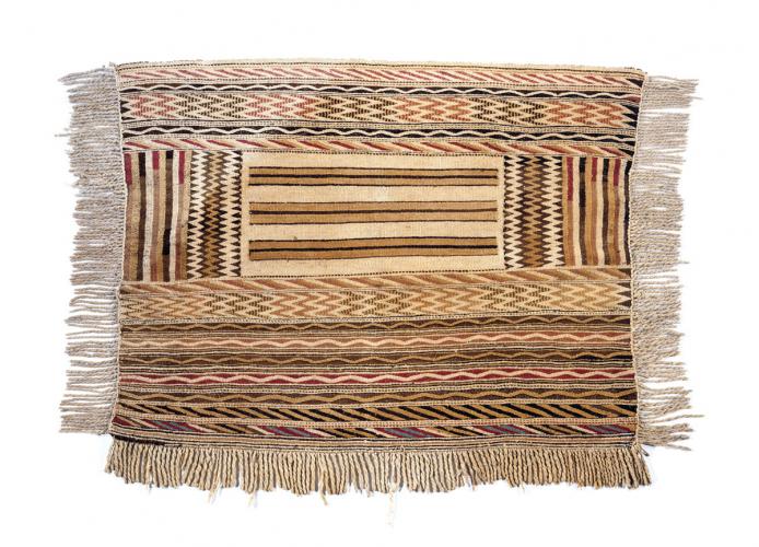 A rectangular woven blanket with a geometric design and a fringe on three sides