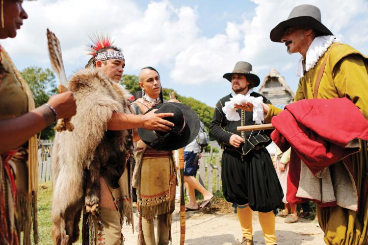 Wampanoag tribesmen and English settlers offer objects for trade in a historical reenactment