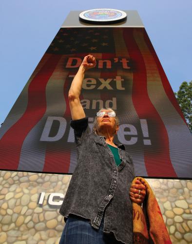 Shinnecock tribal member Margo Thunderbird stands in front of one of two billboards alongside a highway through their territory.