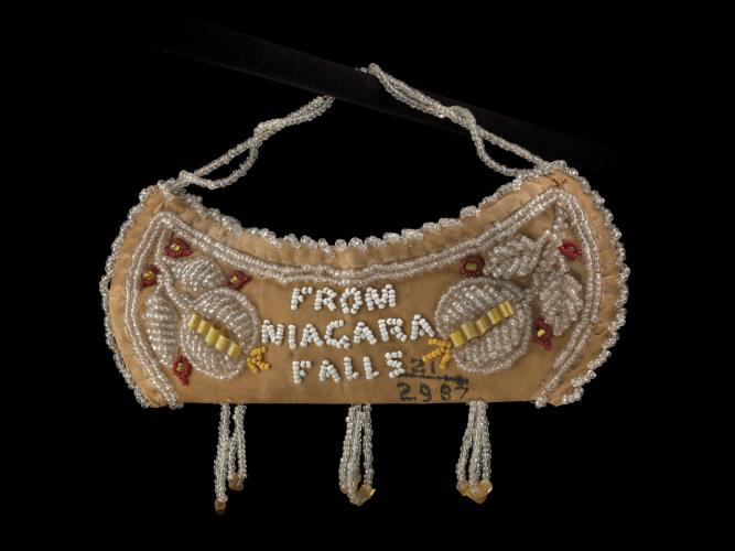A Tuscarora satin bag in the shape of a canoe, with beads forming flowers and the words "From Niagara Falls"