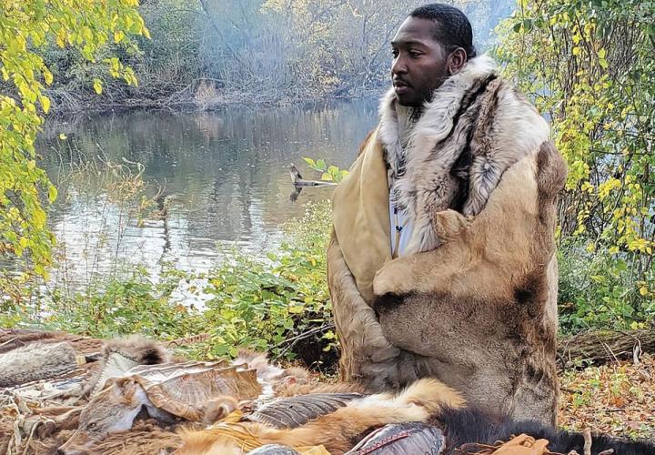 Powhatan Rodrick Bell wearing wolf and elk hides beside the Bronx River.