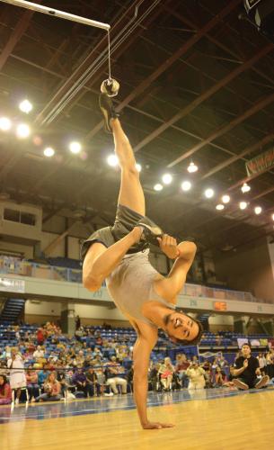 James Wardlow performs a one-handed handstand and kicks a suspended ball 