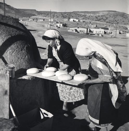 Two women bake traditional bread in an "horno," or oven