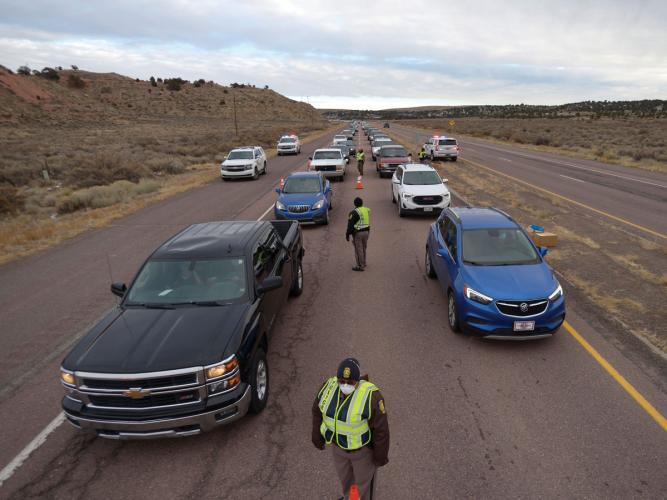 Navajo Nation police officers stop cars at a checkpoint on New Mexico State Highway 264