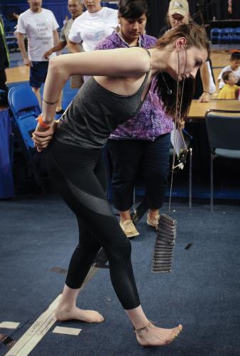 Auna Reed-Lewis carries lead weights dangling from a string that is wrapped around her ear