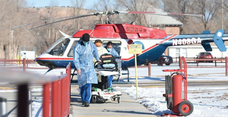 Health care workers wheel a gurney into the Sage Memorial Hospital to evacuate a COVID-19 patient by helicopter
