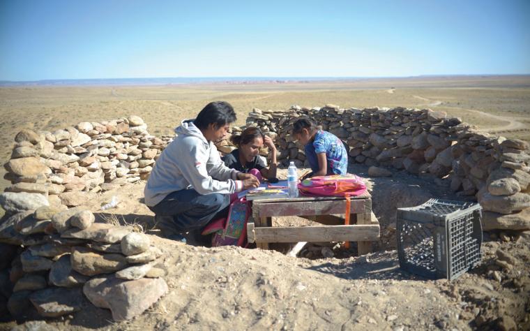 Milton T. Carroll and Wylean Burbank help their daughter Kyla with her schoolwork in a makeshift outdoor classroom