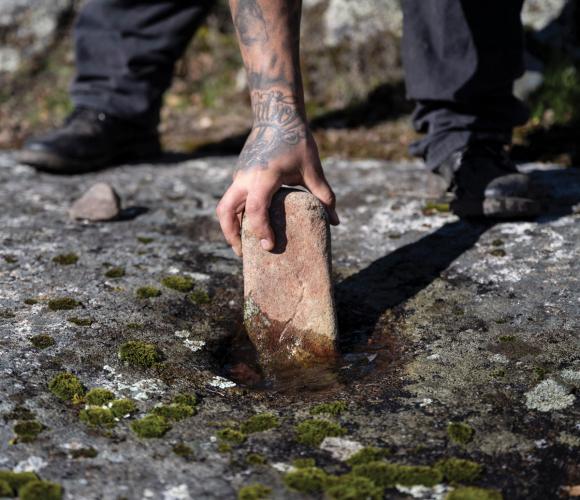Jesse Valdez shows how Miwok villagers once used stone pestles and bedrock mortar holes