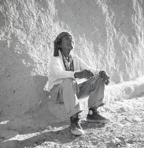 Elderly man sitting against a wall