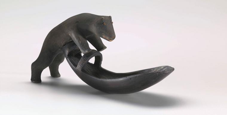 A wood spoon featuring a carving of a jumping grizzly bear