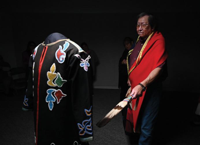Osage Eddy Red Eagle Jr. waves a feather before a beaded coat worn by one of his ancestors
