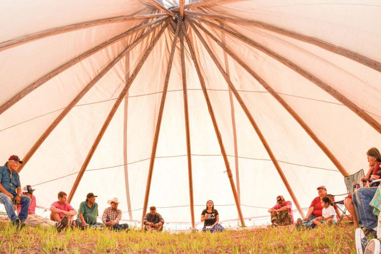 People sitting in a tent at the annual Bears Ears Summer Gathering