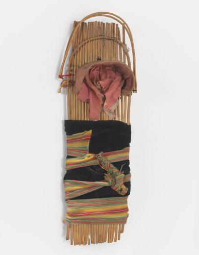 A 100-year-old cradleboard made of wood and wrapped in colorful cloth