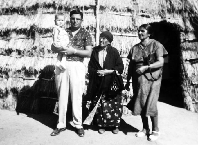 Walter Lamar as an infant is held by his father and is with his great-grandmother and grandmother in front of a traditional Wichita grass dwelling