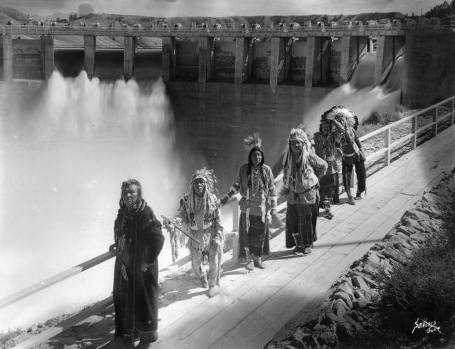 Representatives of the Confederated Salish and Kootenai Tribes stand on a path in front of the recently completed Kerr Dam.