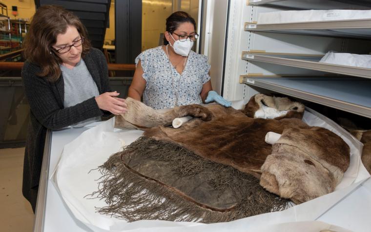 Conservator and collection staff inspect a fur parka stored in a shelf at NMAI's Cultural Resources Center.