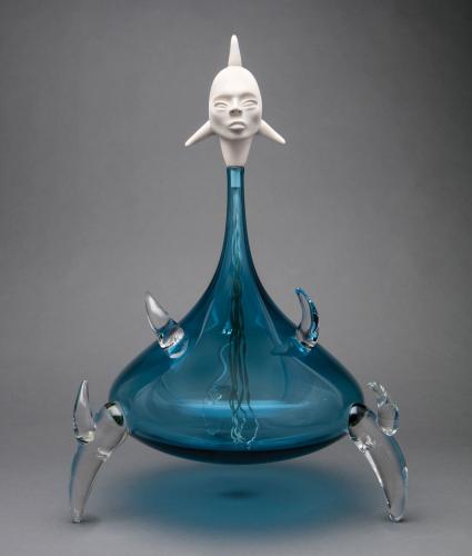 “Translator 2180” glass sculpture with blue, bulbous base, clear feet and hands, and a white head.