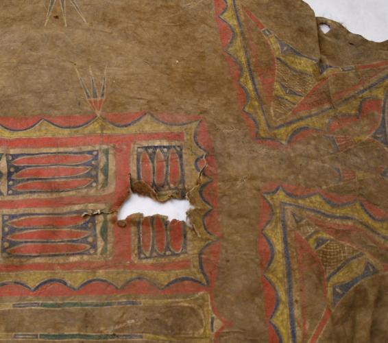Bison hide with red geometric decoration and a hole at its center.