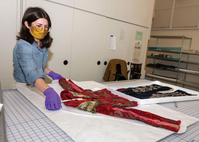 Conservator Hannah Muchnick creates plastic trays to hold a jacket and pair of pants