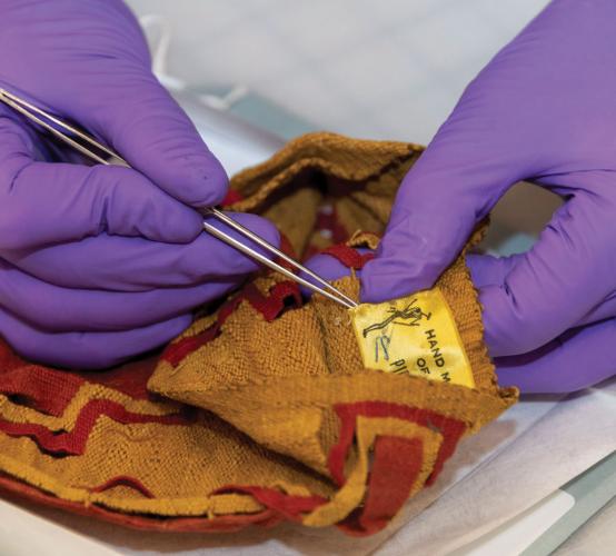 A conservator removes a tag from an article of clothing