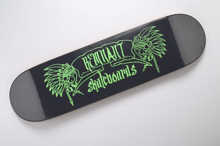 “Green Logo” design by Chris Nieto, with a chief headdress at each end, on black skateboard.
