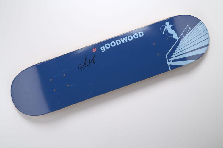 Autographed blue Chedder skateboard with skateboarder image on one end.