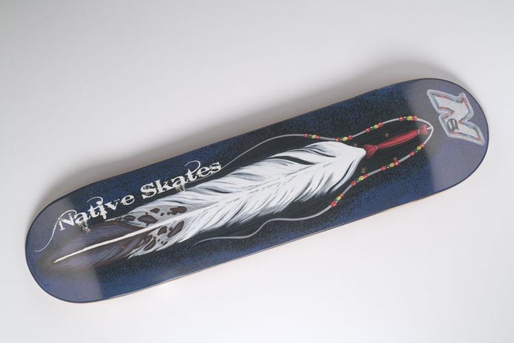 White “Spirit Feather” design by Traci Rabbit on a black skateboard.