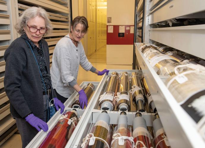 Conservator and volunteer view rolled rugs in shelves at the NMAI's Cultural Resources Center.
