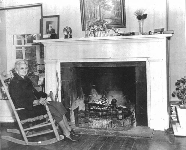 Cobb sits in a wooden rocking chair besides the Hunter's Home fireplace. The image is black and white.